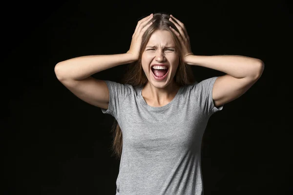 Stressed young woman on dark background — Stock Photo, Image