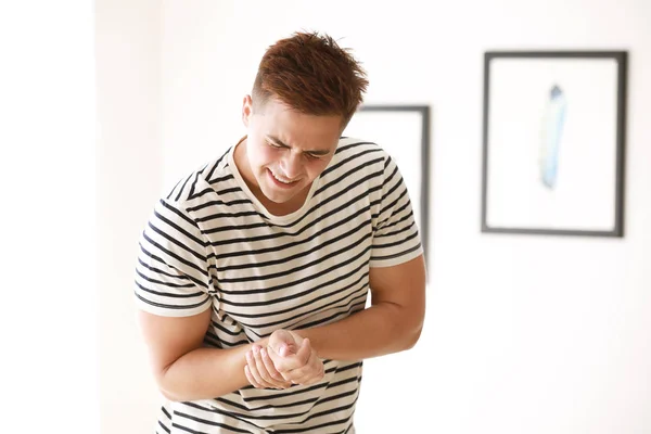 Young man suffering from pain in wrist at home — Stock Photo, Image