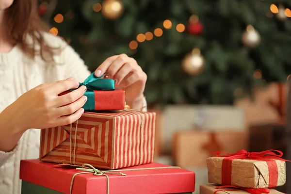 Beautiful young woman opening Christmas gift at home — Stock Photo, Image