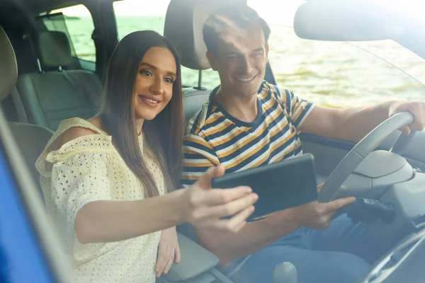 Gelukkig paar het nemen van selfie in hun nieuwe auto, uitzicht vanaf voorruit venster — Stockfoto