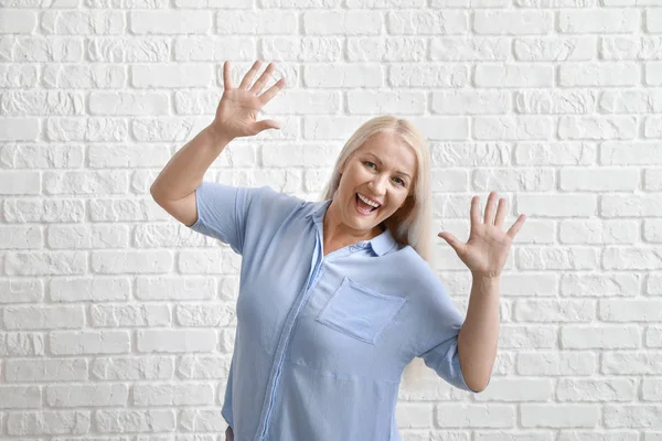 Mulher madura feliz contra parede de tijolo branco — Fotografia de Stock