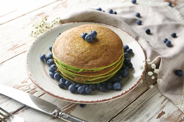 Teller mit grünen Pfannkuchen und frischen Beeren auf weißem Tisch — Stockfoto