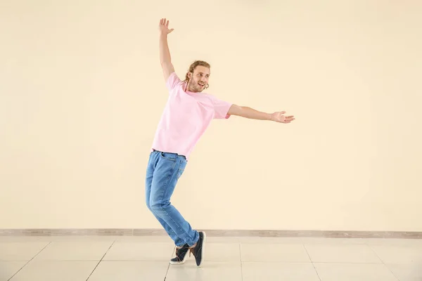 Cool young man dancing against light wall — Stock Photo, Image