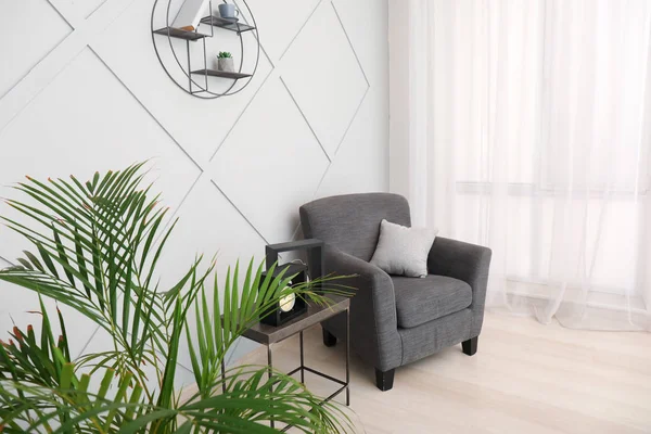 Stilvoller Sessel mit Tisch und Handfläche im Innenraum — Stockfoto