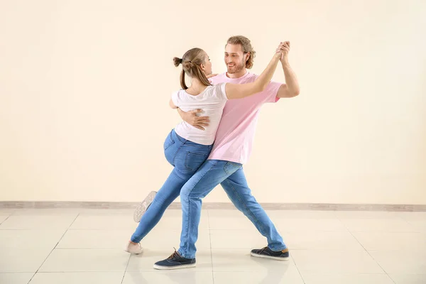 Cool young couple dancing against light wall — Stock Photo, Image