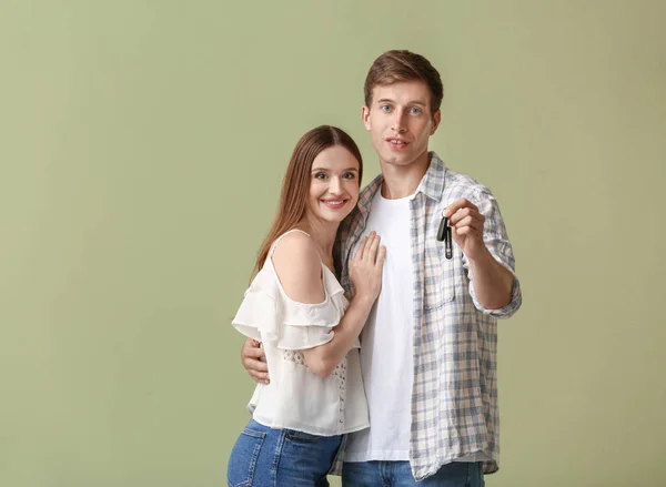 Jovem casal feliz com a chave do carro novo no fundo de cor — Fotografia de Stock