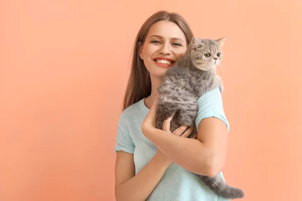 Beautiful young woman with cute cat on color background — Stock Photo, Image