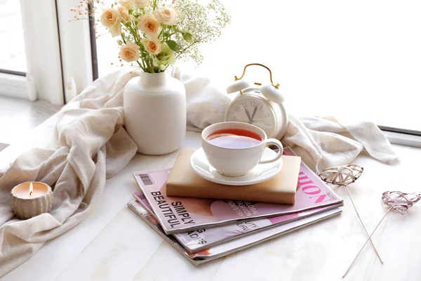 Coupe de thé chaud avec livre et magazines sur le rebord de la fenêtre — Photo