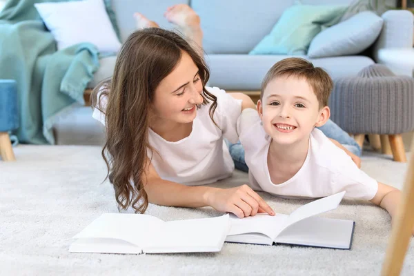 Lille pojken och hans äldre syster läser bok hemma — Stockfoto