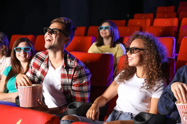 Friends with popcorn watching movie in cinema