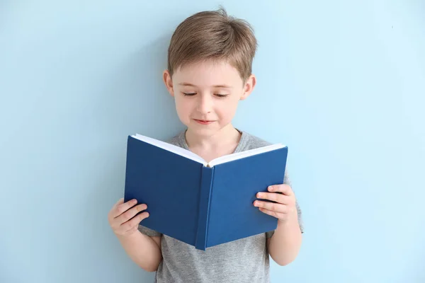 Kleiner Junge liest Buch auf farbigem Hintergrund — Stockfoto