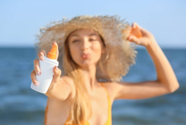 Beautiful young woman with sun protection cream on sea beach