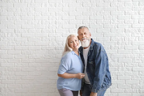 Happy mature couple against white brick wall — Stock Photo, Image