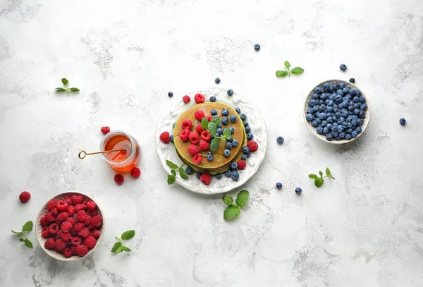 Тарелка с зелеными блинами, свежими ягодами и медом на светлом фоне — стоковое фото