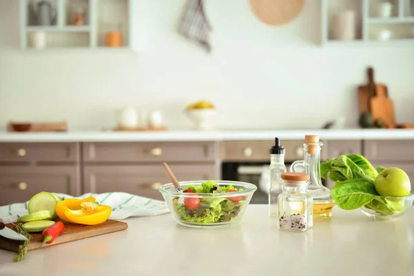 Bowl with salad and ingredients on kitchen table — Stock Photo, Image