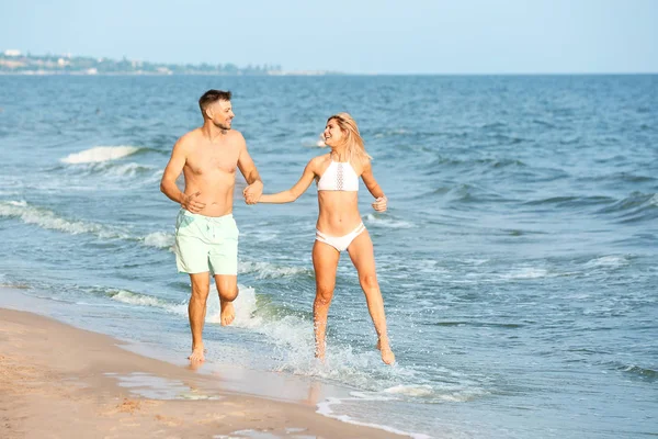 Happy couple running on sea beach — Stock Photo, Image