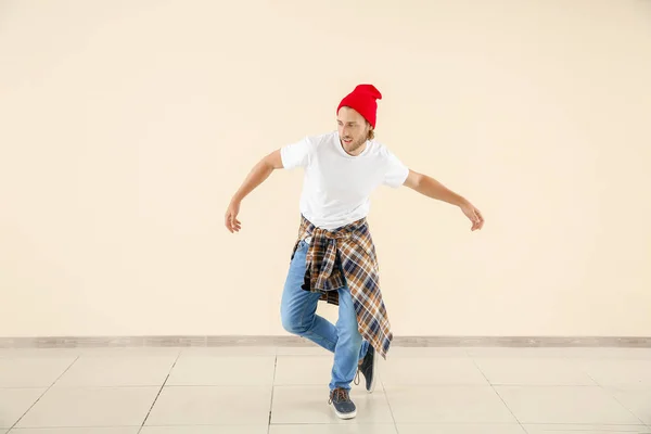 Cool young man dancing against light wall — Stock Photo, Image