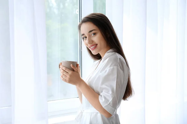 Ранок красивої молодої жінки п'є каву біля вікна — стокове фото