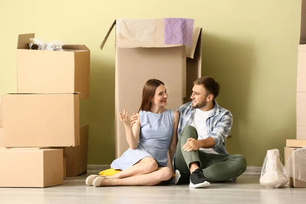 Glückliches junges Paar mit Habseligkeiten auf dem Boden in ihrem neuen Haus — Stockfoto