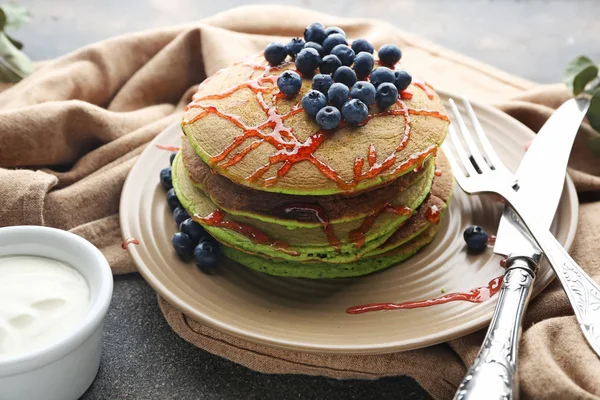Teller mit grünen Pfannkuchen, Beerenmarmelade und Sauce auf grauem Hintergrund — Stockfoto