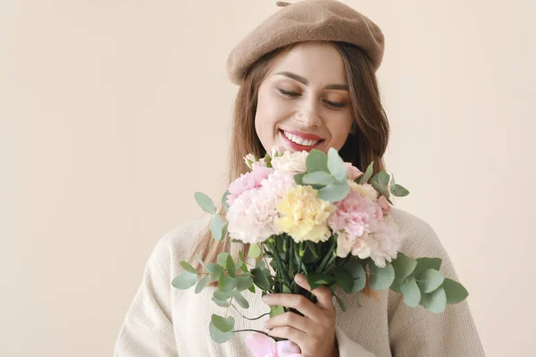 Belle jeune femme avec bouquet de fleurs d'oeillet sur fond clair — Photo