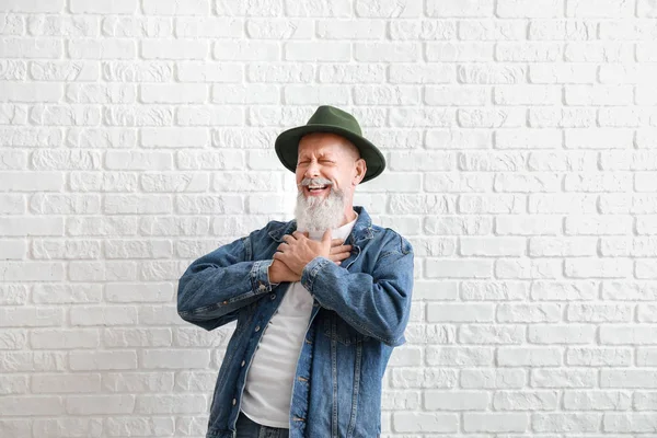 Laughing mature man against white brick wall — Stock Photo, Image
