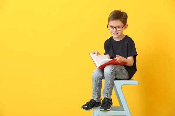 Kleiner Junge liest Buch auf farbigem Hintergrund — Stockfoto