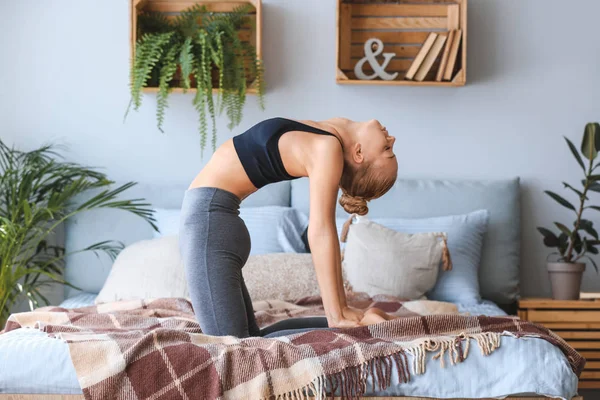 Mujer joven practicando yoga en la cama en casa — Foto de Stock