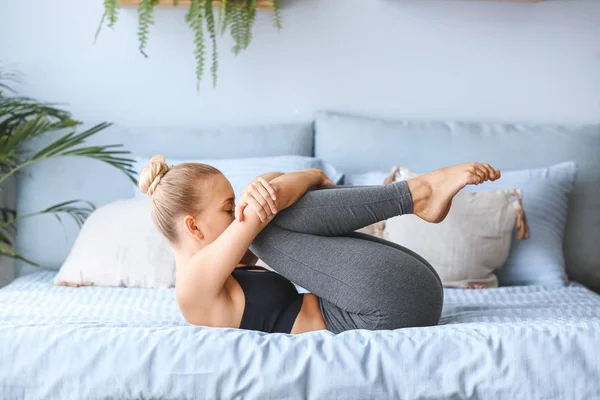 Young woman practicing yoga on bed at home — Stock Photo, Image