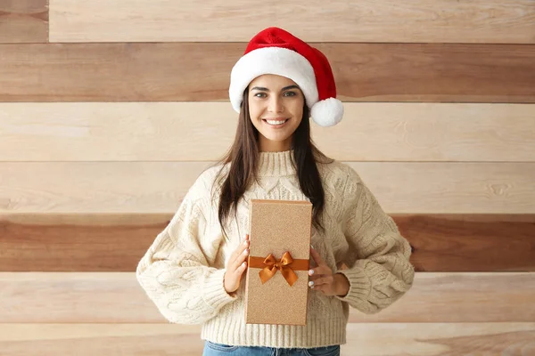 Schöne junge Frau mit Weihnachtsgeschenk auf Holzgrund — Stockfoto