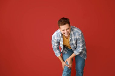 Genç adam renk arka plan üzerinde diz ağrısı muzdarip