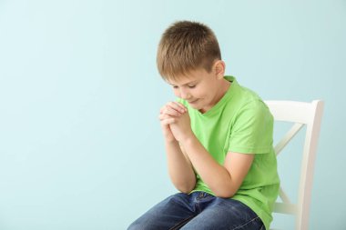 Renkli arka planda dua eden küçük çocuk