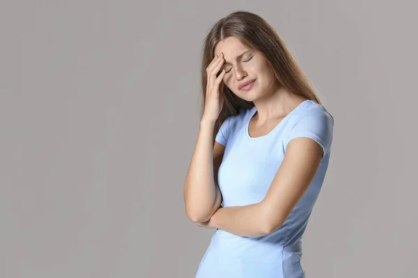 Stressed young woman on grey background — Stock Photo, Image