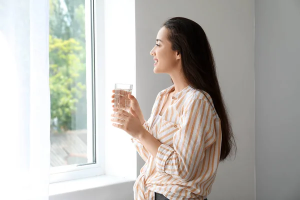 Ранок красивої молодої жінки п'є воду біля вікна — стокове фото