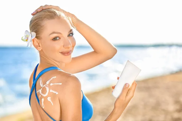 Hermosa mujer joven con crema de protección solar en la playa de mar — Foto de Stock