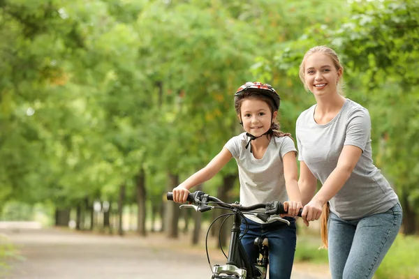 Matka učí svou dceru jezdit na kole venku — Stock fotografie