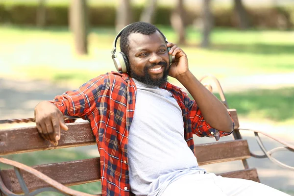 African-American man listening to music in park — Stock Photo, Image