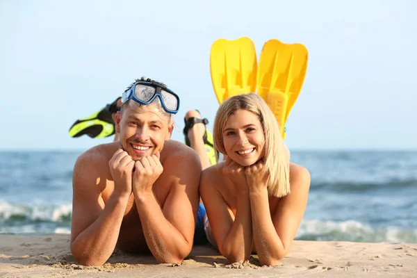 Happy couple with snorkeling mask and paddles at sea resort — Stock Photo, Image