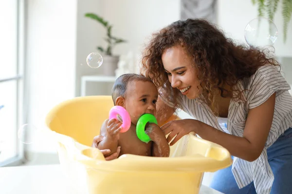 Joven madre afroamericana lavando a su bebé en casa — Foto de Stock