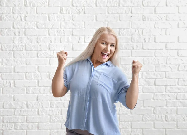 Happy mature woman against white brick wall — Stock Photo, Image