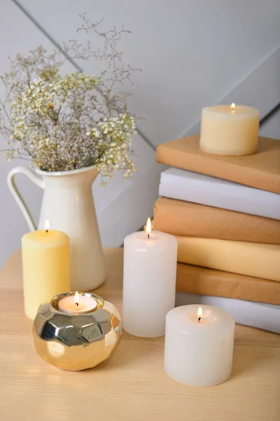 Красивые горящие свечи с книгами на столе в комнате — стоковое фото