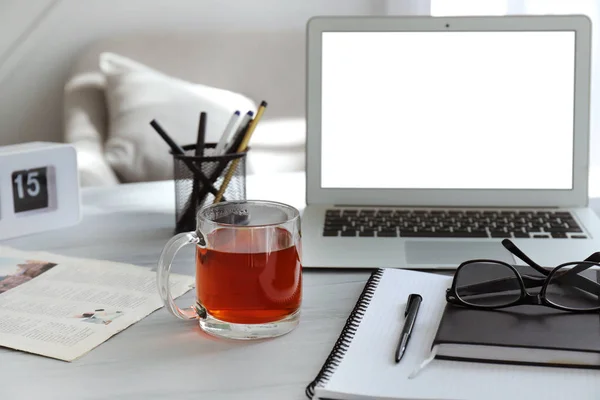 Coupe avec thé chaud, ordinateur portable et papeterie sur la table — Photo