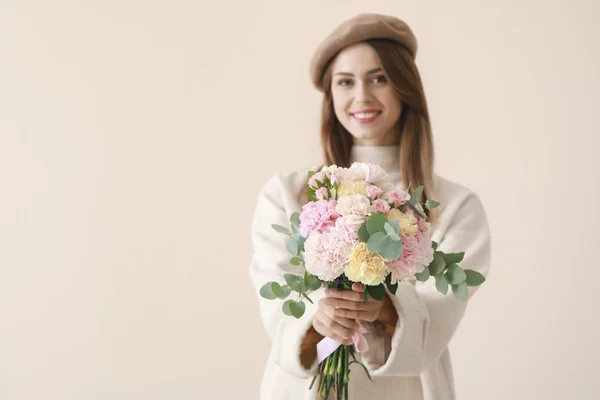 Beautiful young woman with bouquet of carnation flowers on light background — Stock Photo, Image