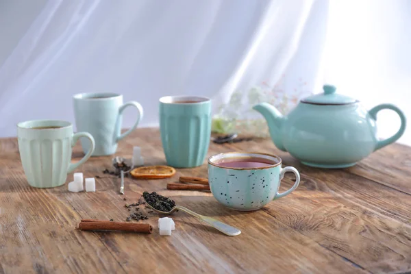 Cups and teapot with hot beverage on wooden table — Stock Photo, Image