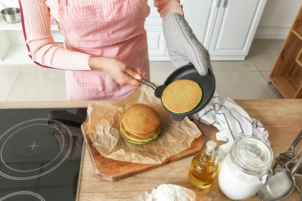 Woman preparing tasty green pancakes in kitchen, closeup — Stock Photo, Image