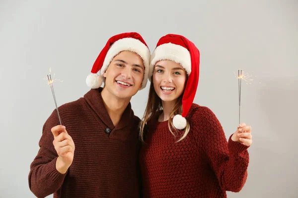 Lyckligt ungt par med Christmas tomtebloss på ljus bakgrund — Stockfoto