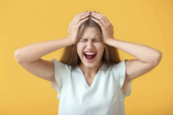 Stressed young woman on color background — Stock Photo, Image