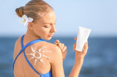 Deniz plajında güneş koruma kremi ile güzel genç kadın