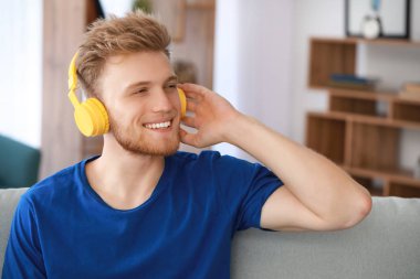 Evde müzik dinleyen yakışıklı genç adam.