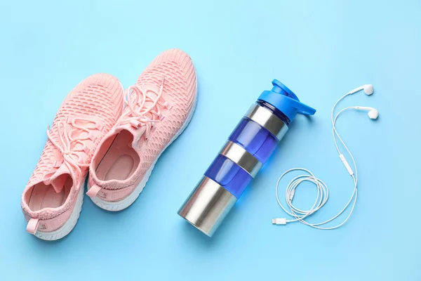 Бутылка спортивной воды, обувь и наушники на цветном фоне — стоковое фото